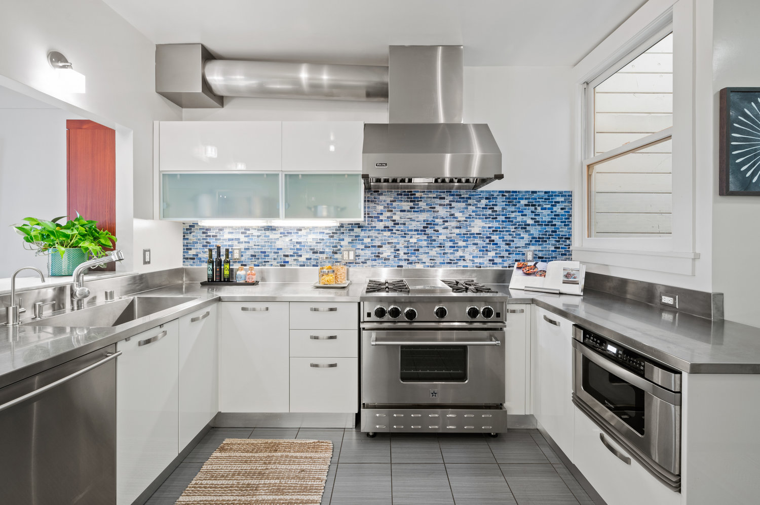 Property Photo: Kitchen the has all stainless steel appliances and a beautiful light blue tile backsplash. .