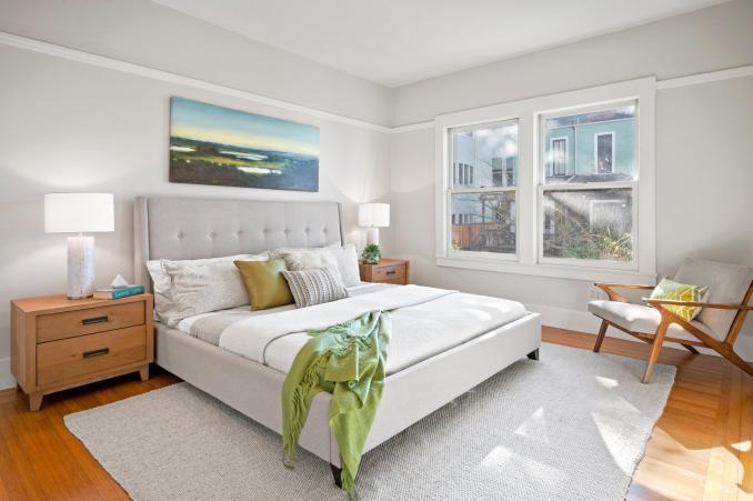 Property Thumbnail: Primary bedroom that has large king size bed and two bedside tables. There are two large windows that look over yard. Lots of natural light. 