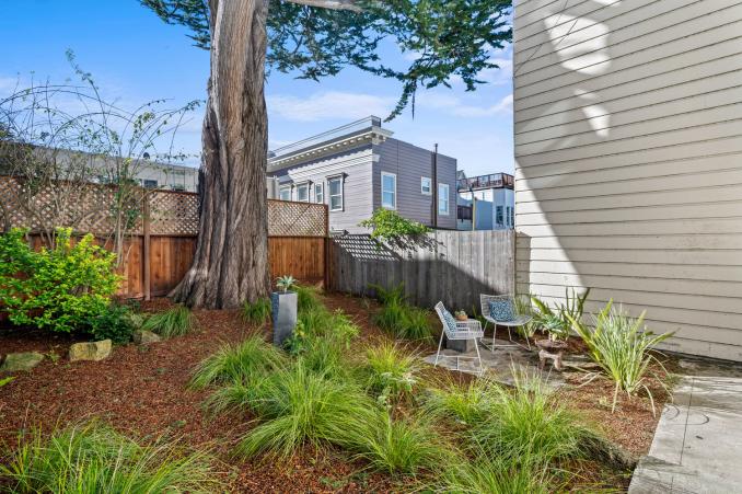 Property Thumbnail: Looking at beautiful yard from side breezeway. There is large tree, sitting area, and lots of greenery. 