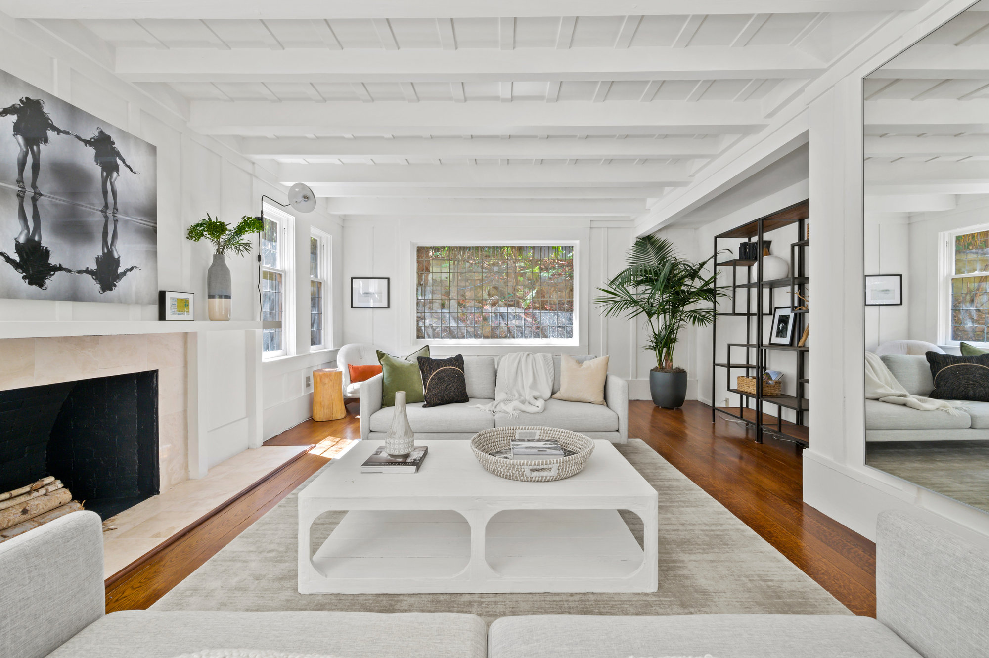 Property Photo: Large living room with lots of wood detailing. All wood is white except the natural hardwood floors. 