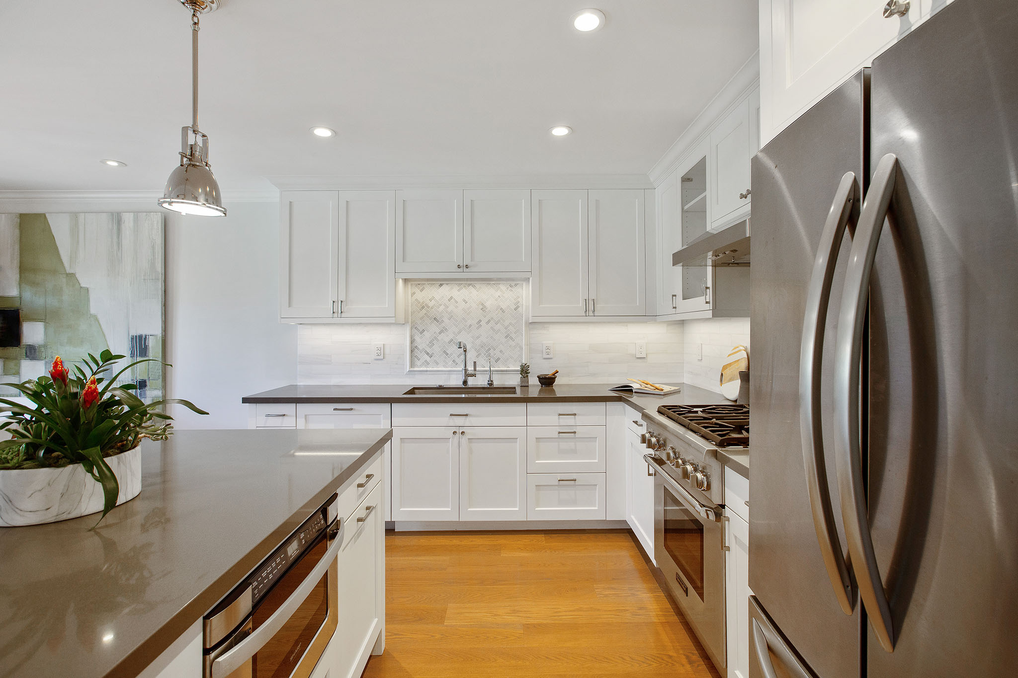 Property Photo: Kitchen has hardwood floors, all stainless appliances with all white cabinetry. 