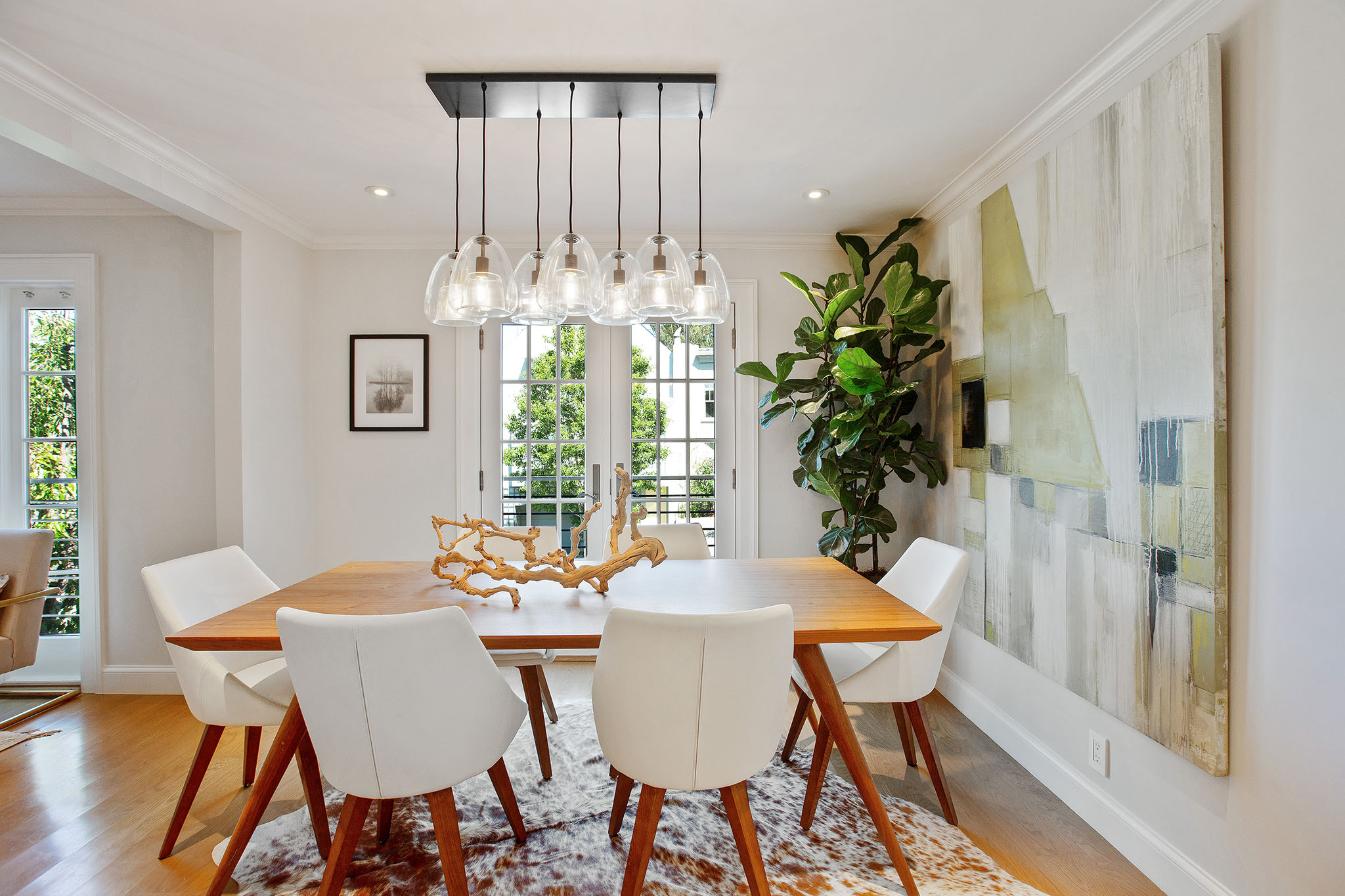 Property Photo: Centered photo of dining table. There is a modern glass light fixture above dining table. 