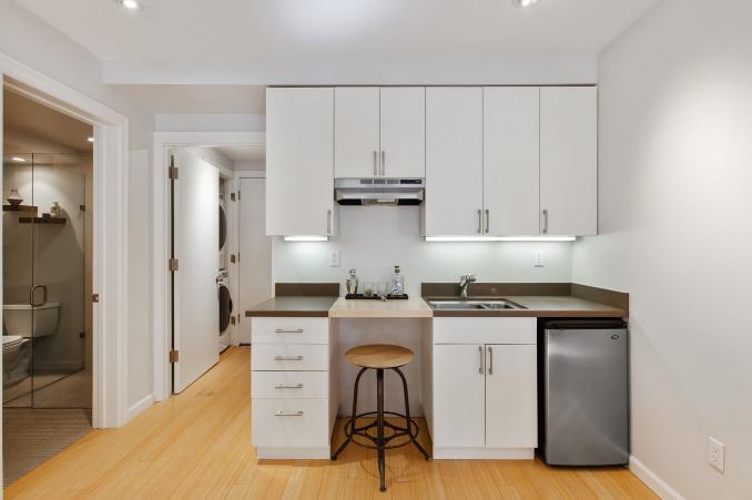 Property Thumbnail: Centered photo of wet bar. There are upper and lower white cabinets. 