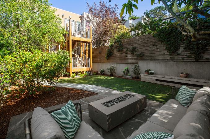 Property Thumbnail: Photo of sitting area in the back yard. There is an L shaped couch with outdoor fireplace. 