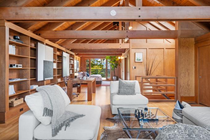 Property Thumbnail: Looking over sitting area in upper level. You see over a wooden desk and bedroom area to the large french doors on the other side of the room. 