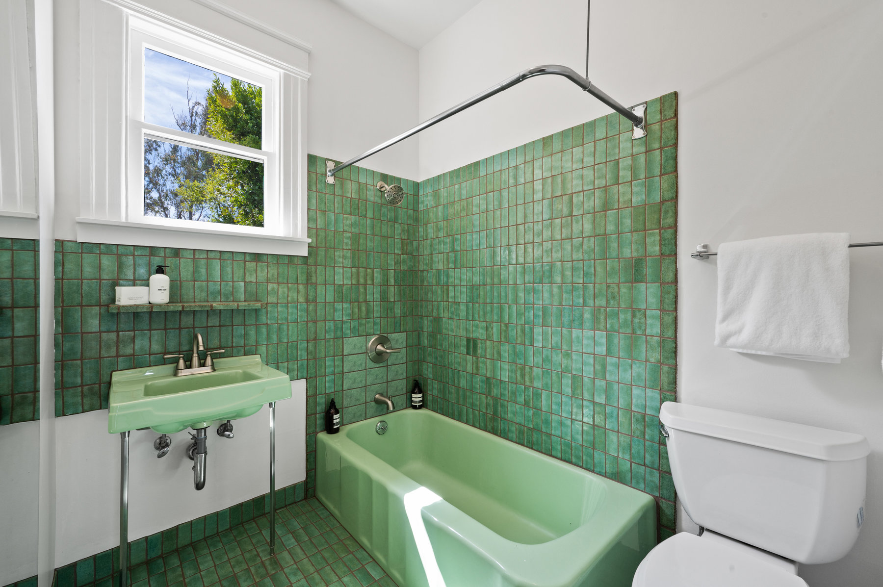 Property Photo: Guest bathroom has green Heath Tile floors and wall around tub and sink. 