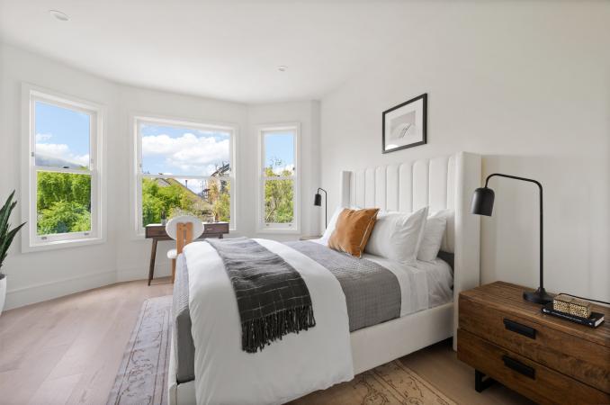 Property Thumbnail: Guest bedroom has large bay windows with small desk under. There is a queen bed with two bedside tables.