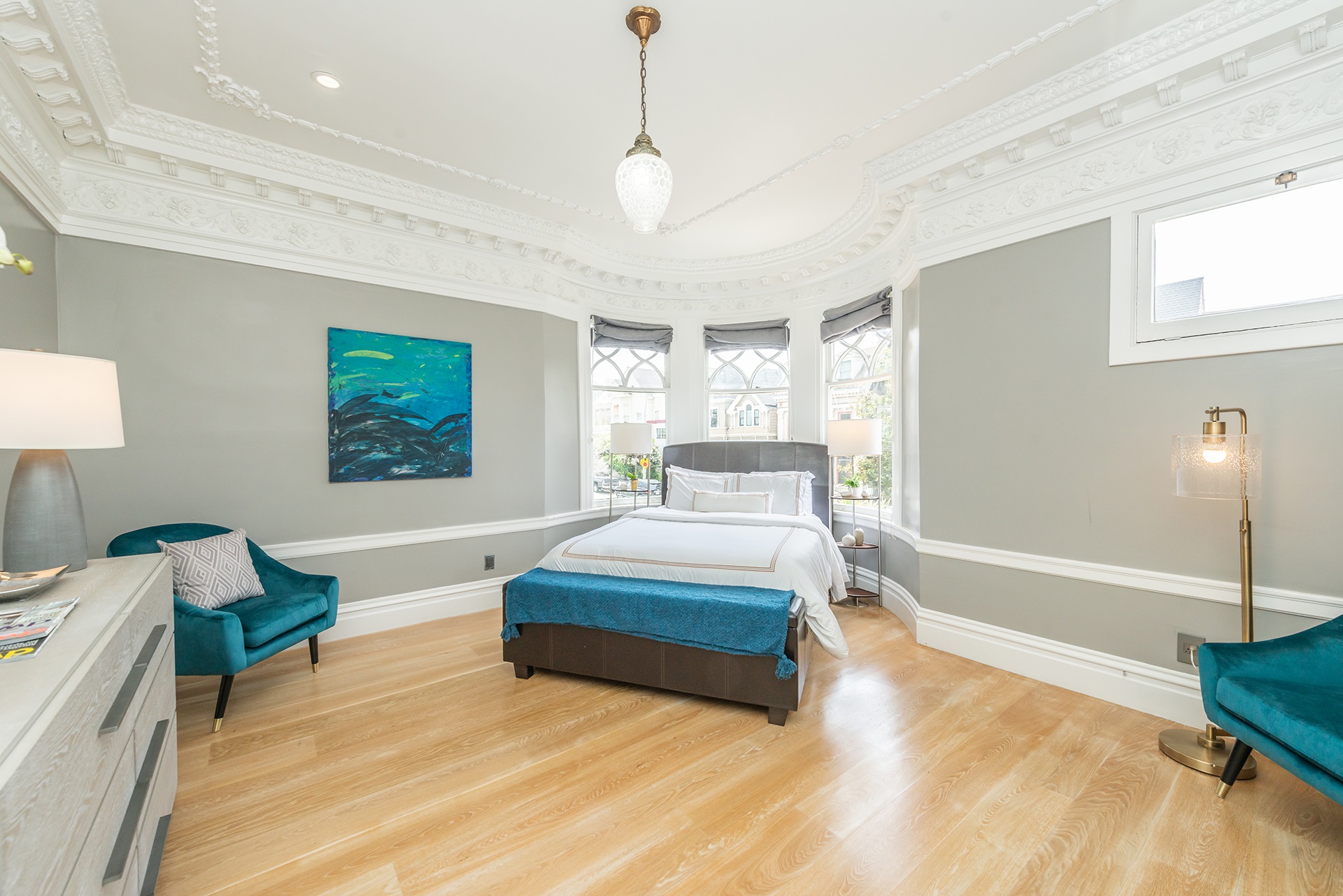 Property Photo: Primary bedroom that has bed centered under bay windows. There is stunning crown molding detail on the ceiling in this room. 