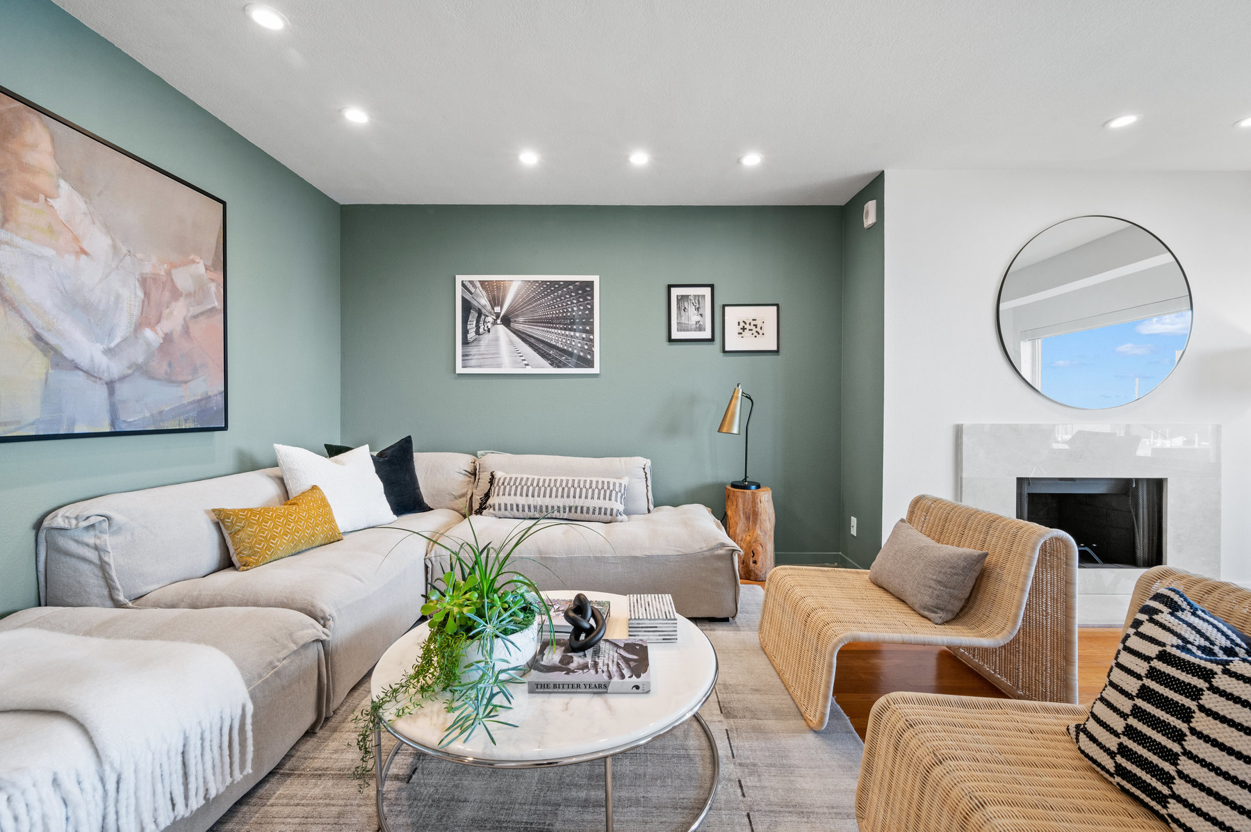 Property Photo: Living room area has pretty light green statement walls. L shaped couch with oval coffee table and two sitting chairs. 