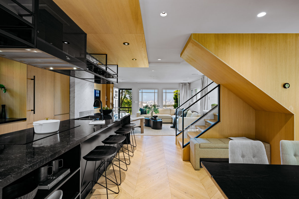 Property Photo: Looking past kitchen to the front living room. There is a staircase to the right.