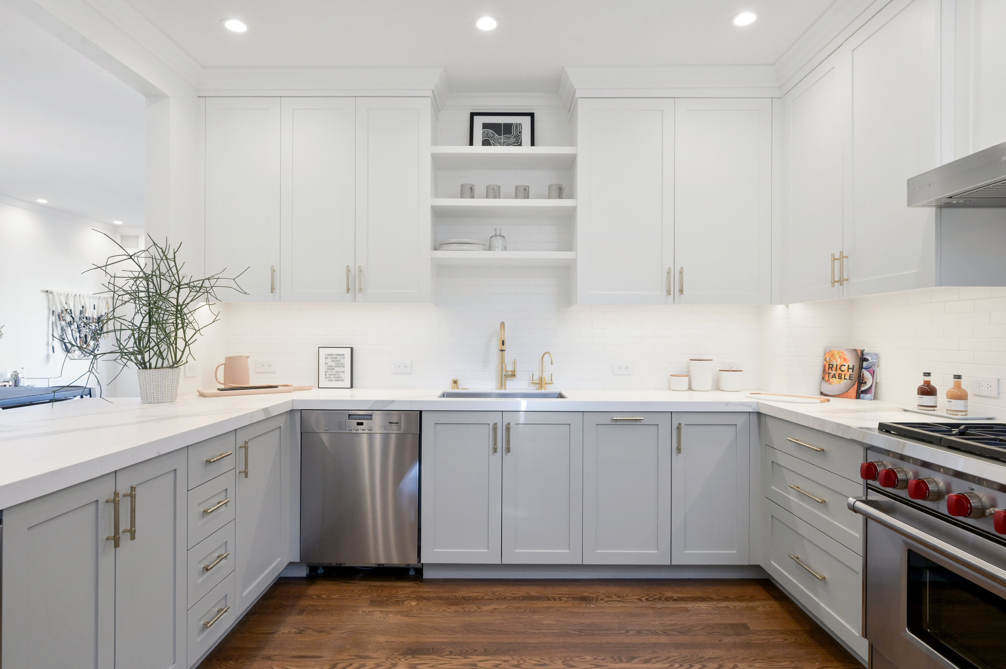 View of a luxurious U-shaped kitchen with white counter tops and light grey cabinets
