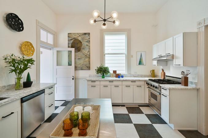 Property Thumbnail: View of the kitchen, featuring large black and white tile flooring and white cabinets