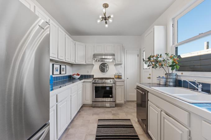 Property Thumbnail: View of the galley-style kitchen, featuring white cabinetry 