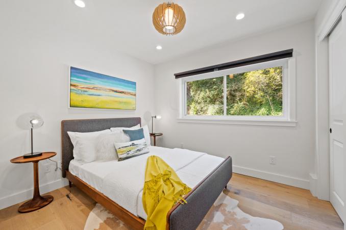 Property Thumbnail: Bedroom three, featuring a large window, mid-century light fixture, and wood floors