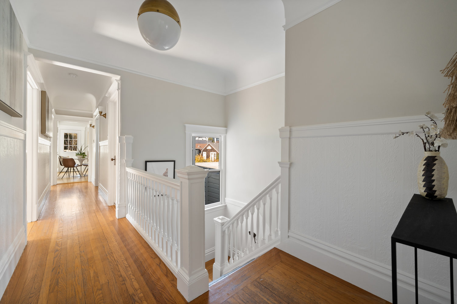 Property Photo: Hallway, featuring wood floors and a pretty white wood staircase leading down