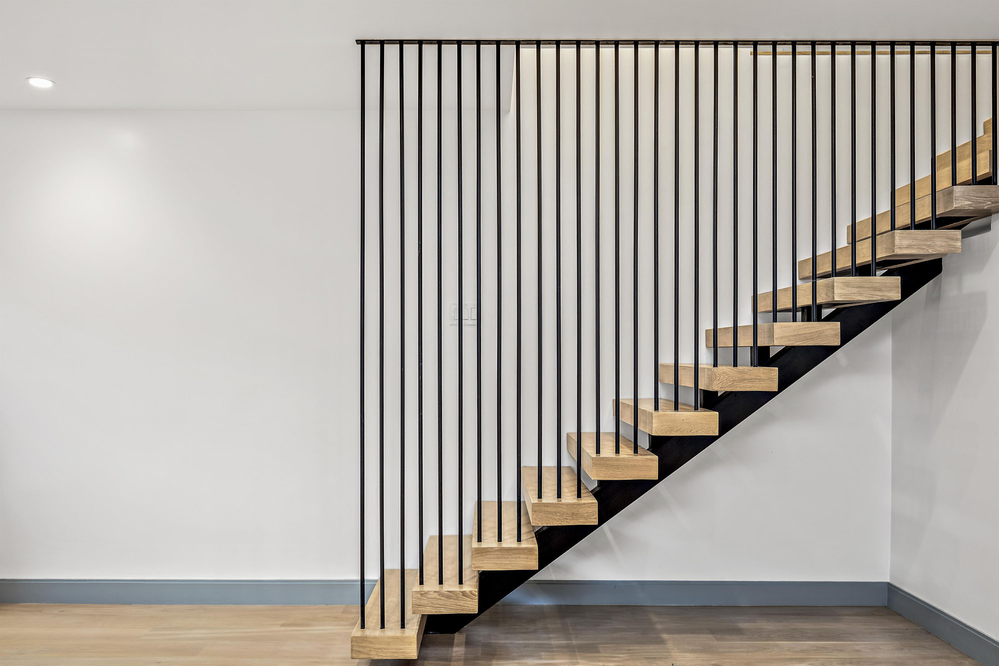 Property Photo: Staircase that leads to lower level. Stunning step to ceiling steel rod detail on side of steps. 