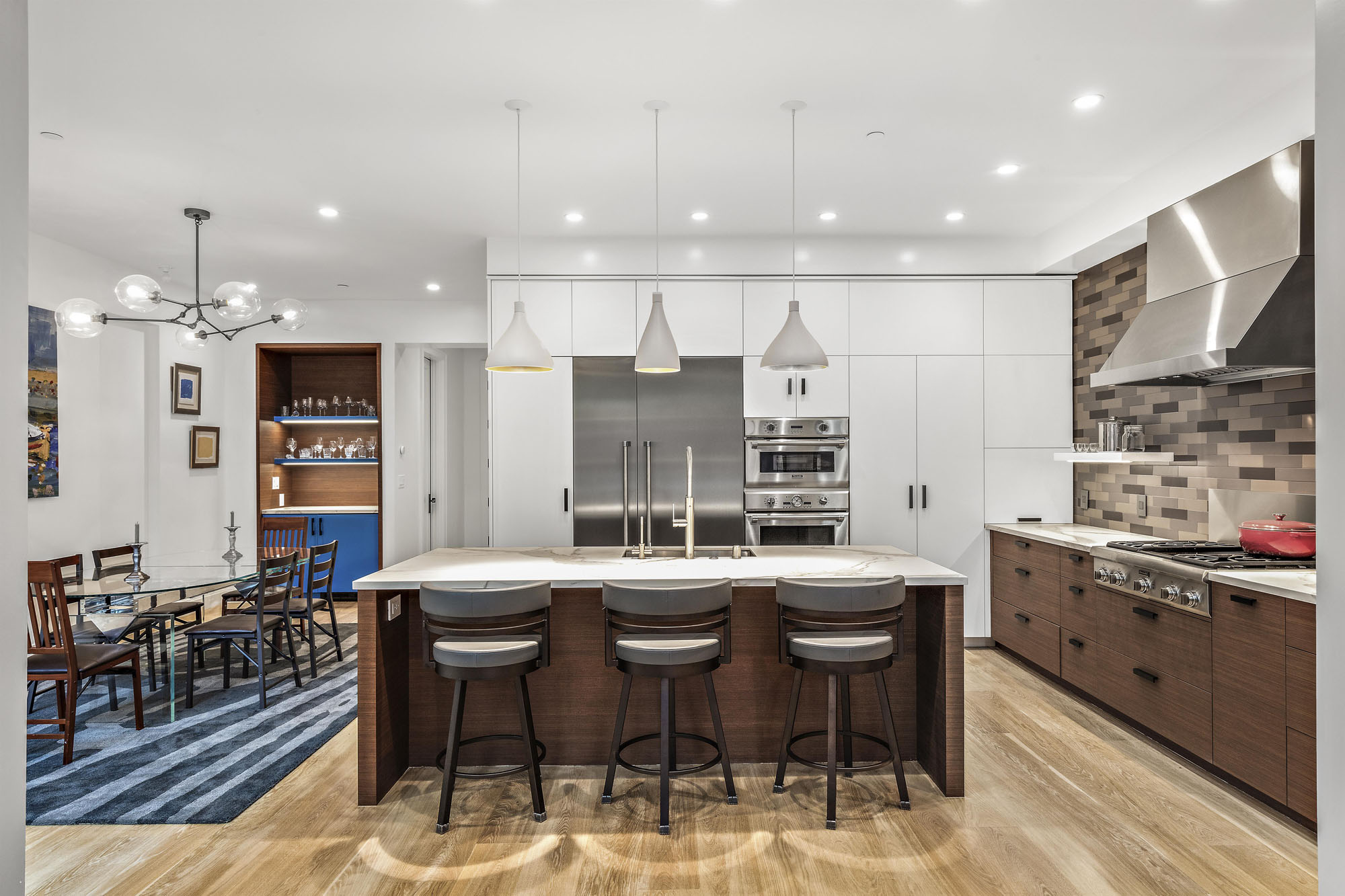 Property Photo: Looking at kitchen area from living room. The island is center in this photo with the three stool and light pendants.
