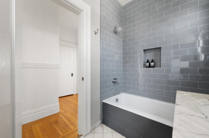 Property Thumbnail: There is grey tile detail surrounding tub, and white tile floors. Bathroom has been updated. 
