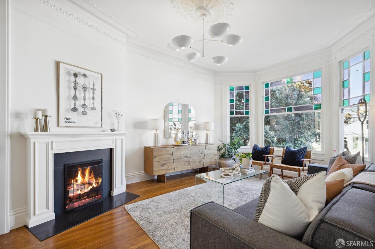 Property Photo: Living room has fireplace and hardwood throughout. There is stained glass detail on upper front bay window. 