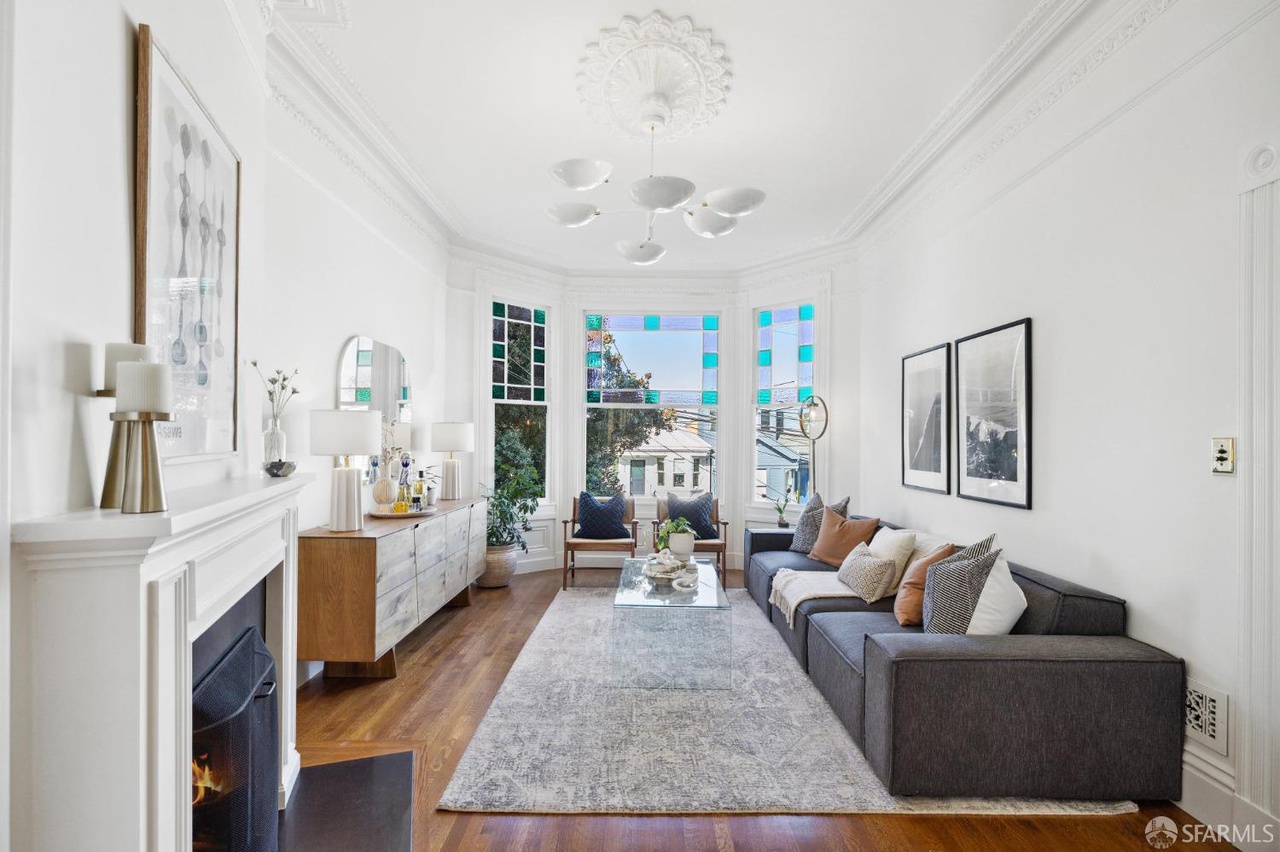 Property Photo: Living room has lots of crown molding detail. There is large couch on right wall. 