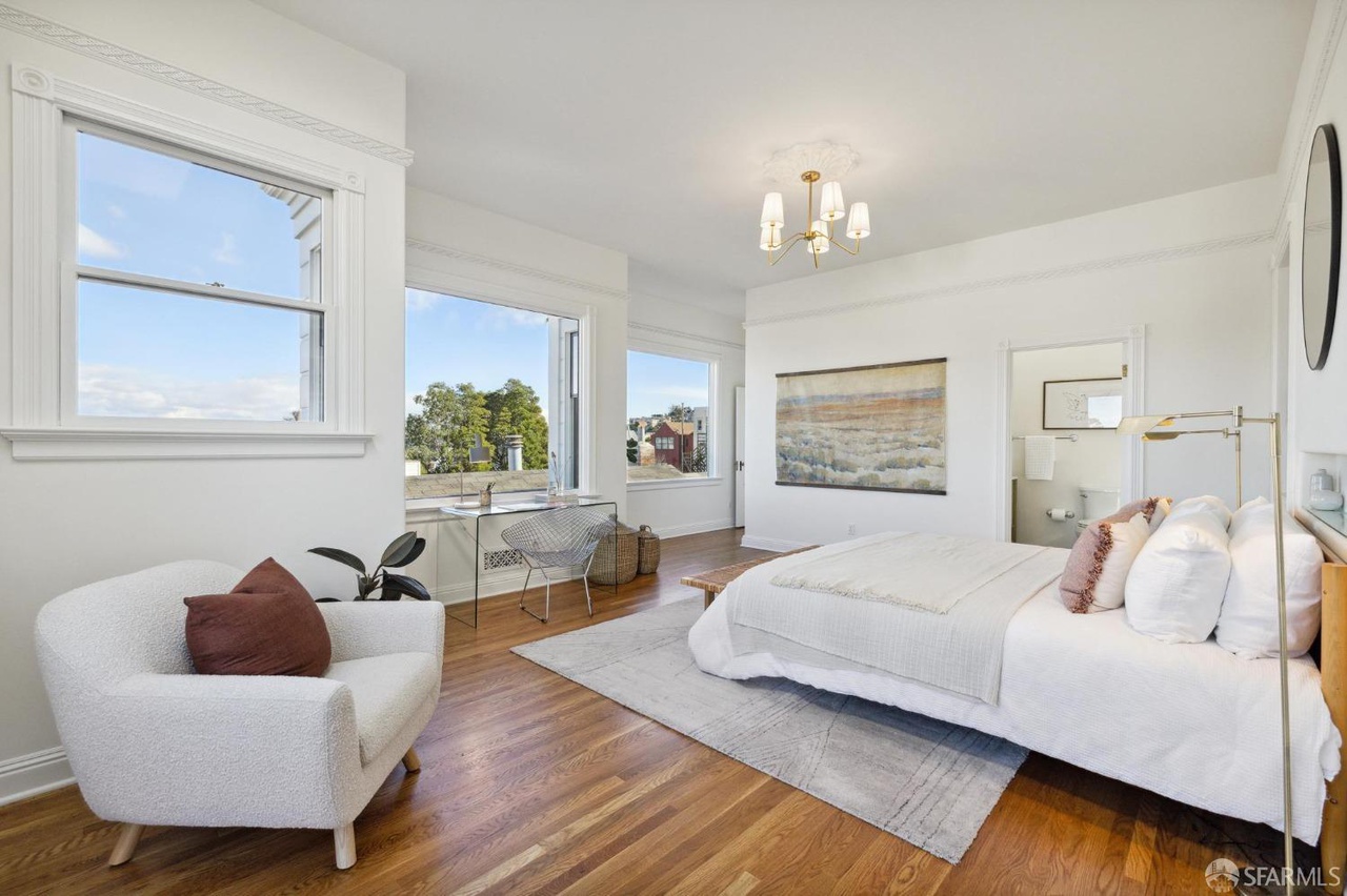 Property Photo: Primary has small sitting area near french doors. Looking over bedroom you see the door to on suit bathroom. 