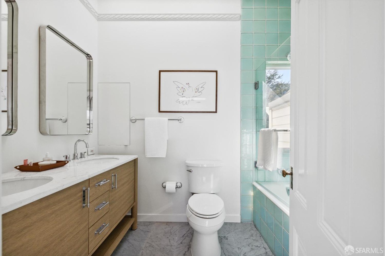 Property Photo: On suite bathroom has grey chevron grey tile floors and shower has teal green tile detail. 