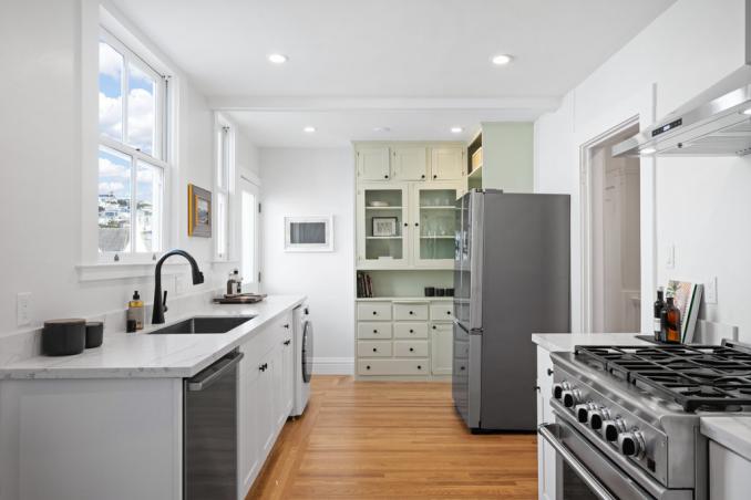 Property Thumbnail: Kitchen has large windows that let in lots of light and there is a built in cabinet at back side of room. 