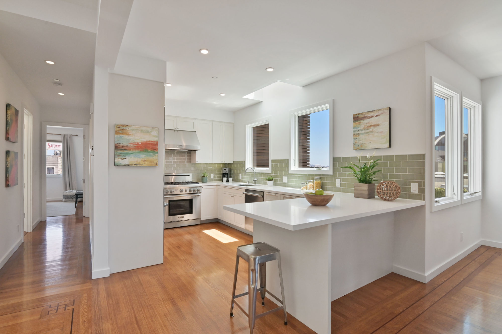 Property Photo: Kitchen, with lots of natural light, wood floors, and light green tile backsplash