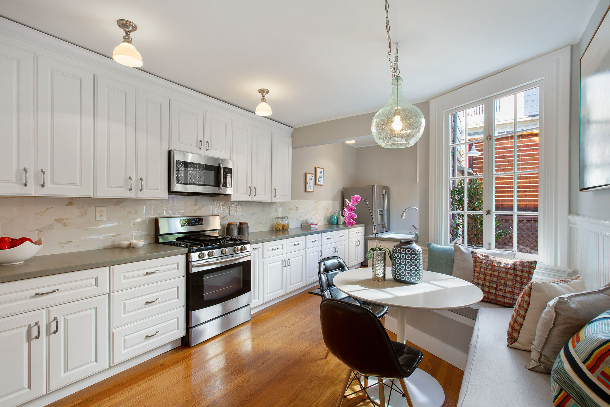 Property Photo: View of the kitchen, featuring a long row of white cabinets and wood floors