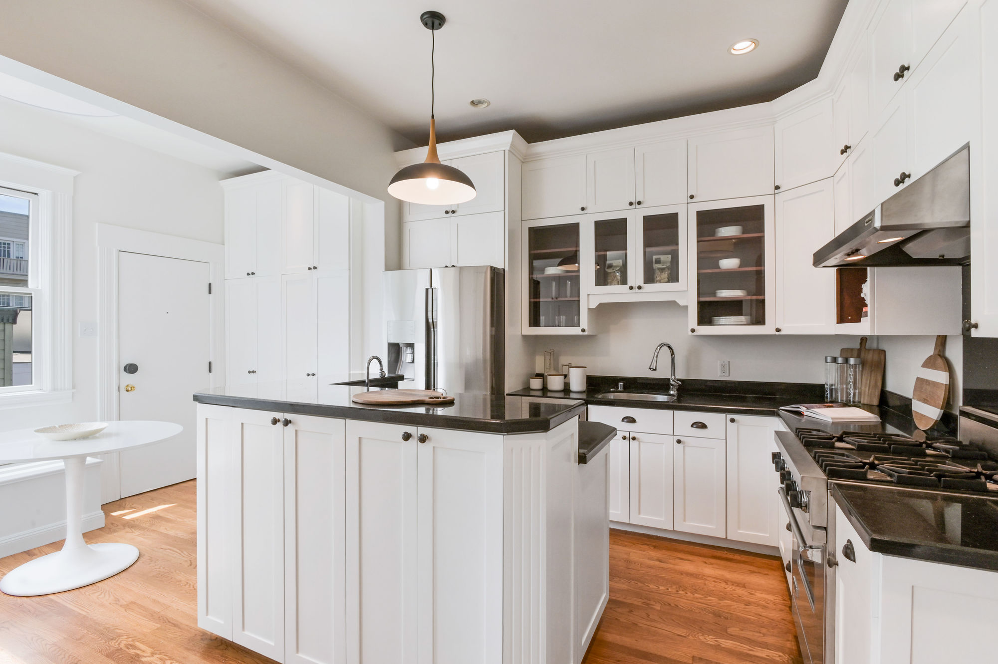 Property Photo: View of the kitchen, featuring white cabinets and wood floors