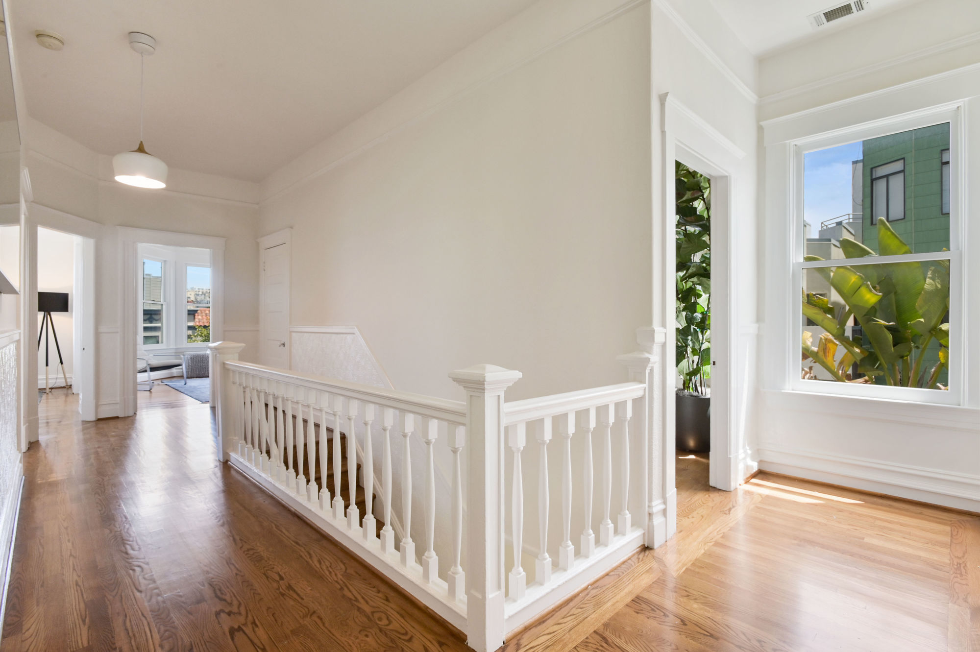 Property Photo: View of the sun-lit hallway, featuring white railing for steps leading down