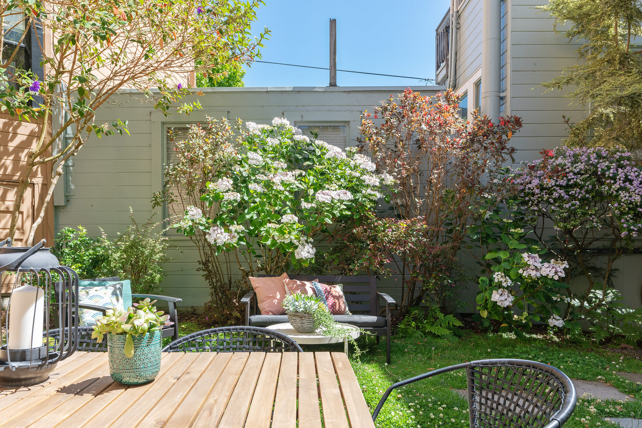 Property Photo: View from the out door dining space, featuring lush plants and blooming bushes 