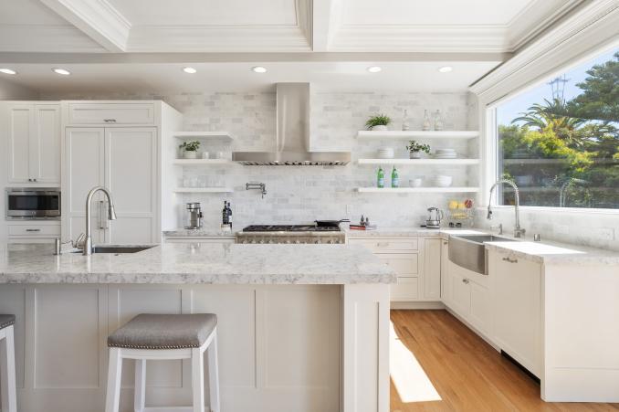 Property Thumbnail: View of the kitchen, featuring luxurious white cabinetry, island, and a large window over the sink