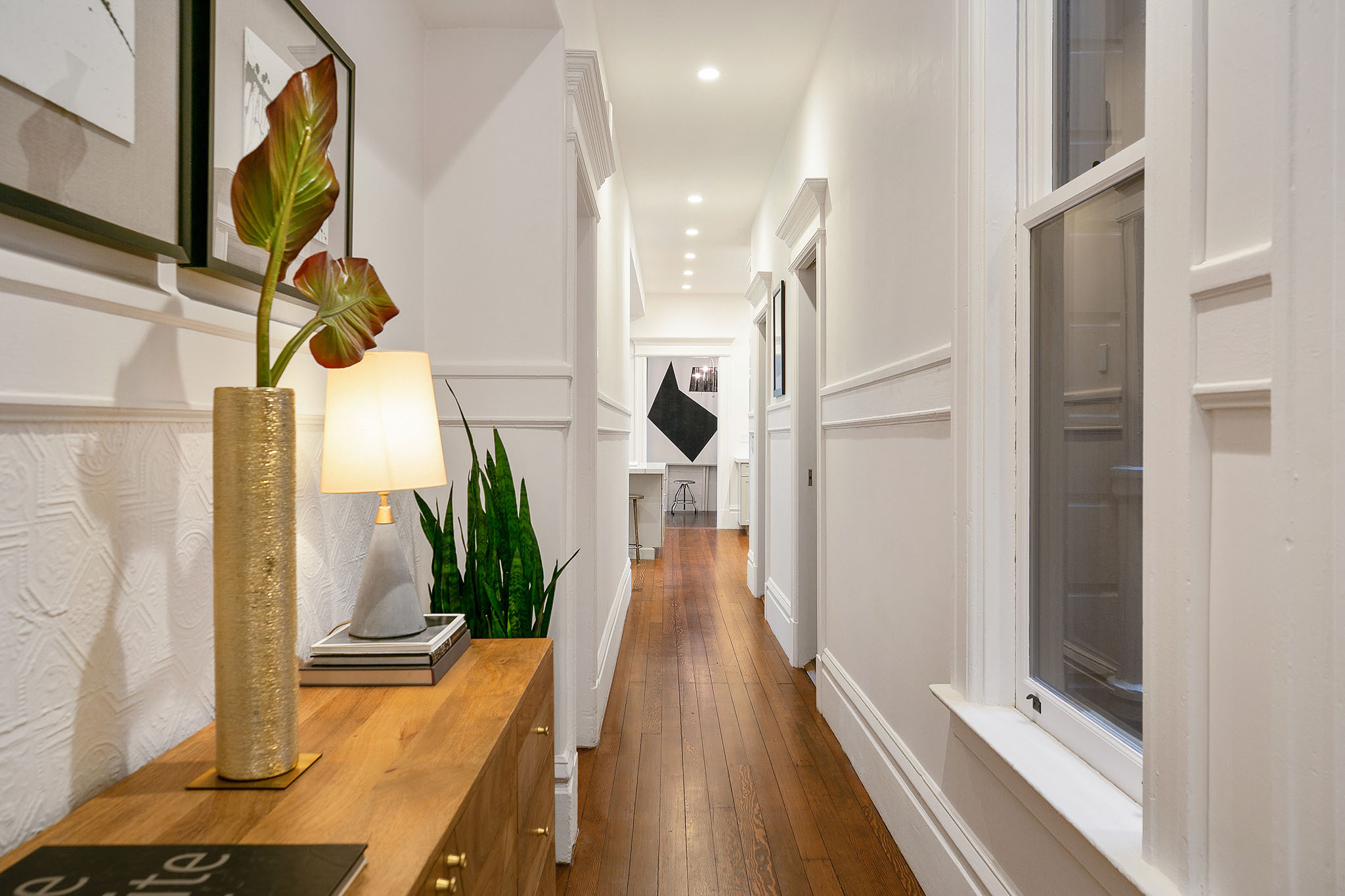Property Photo: View of the hallway, featuring wood floors and white wainscoting