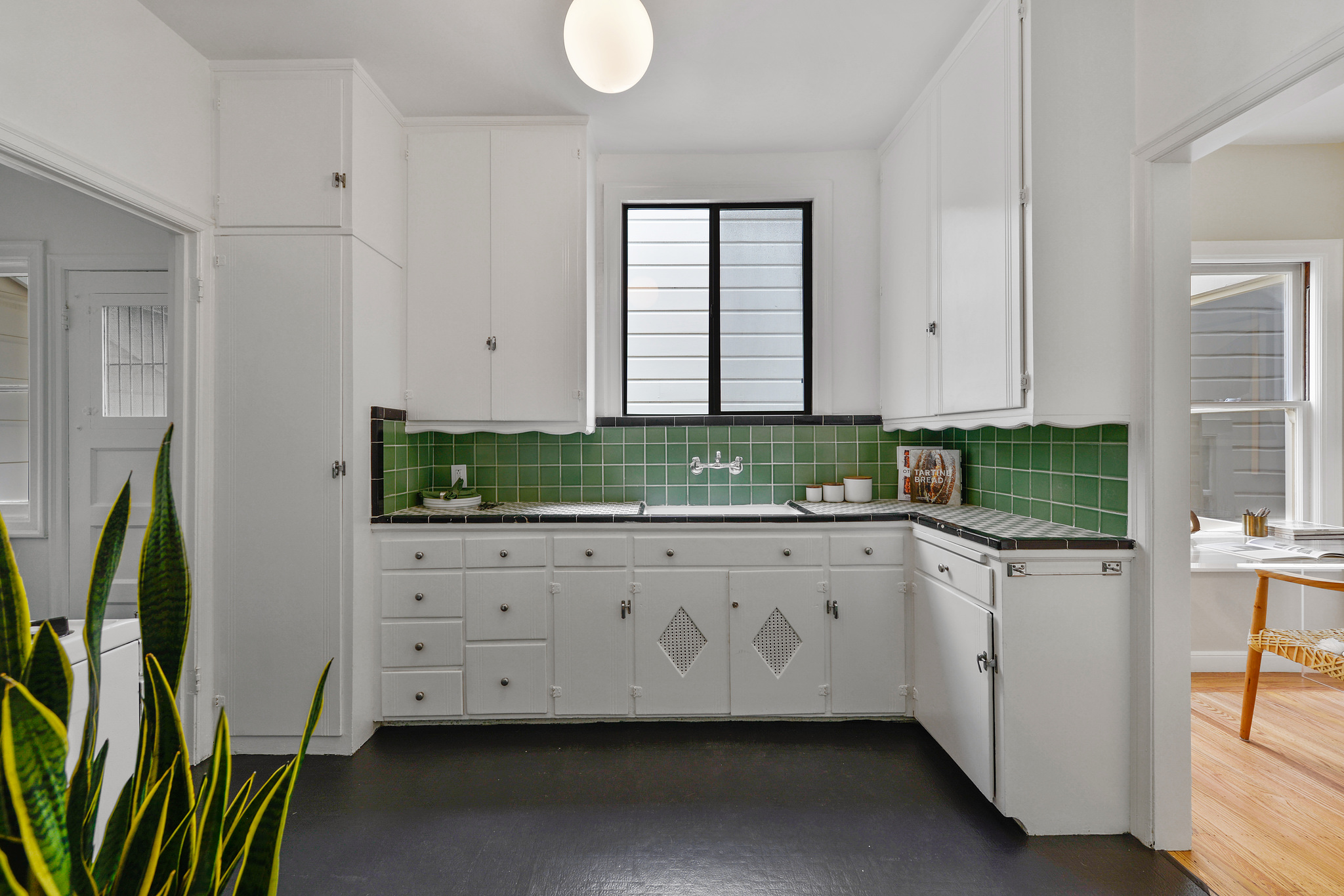 Property Photo: Kitchen with green tile backsplash and white cabinets 