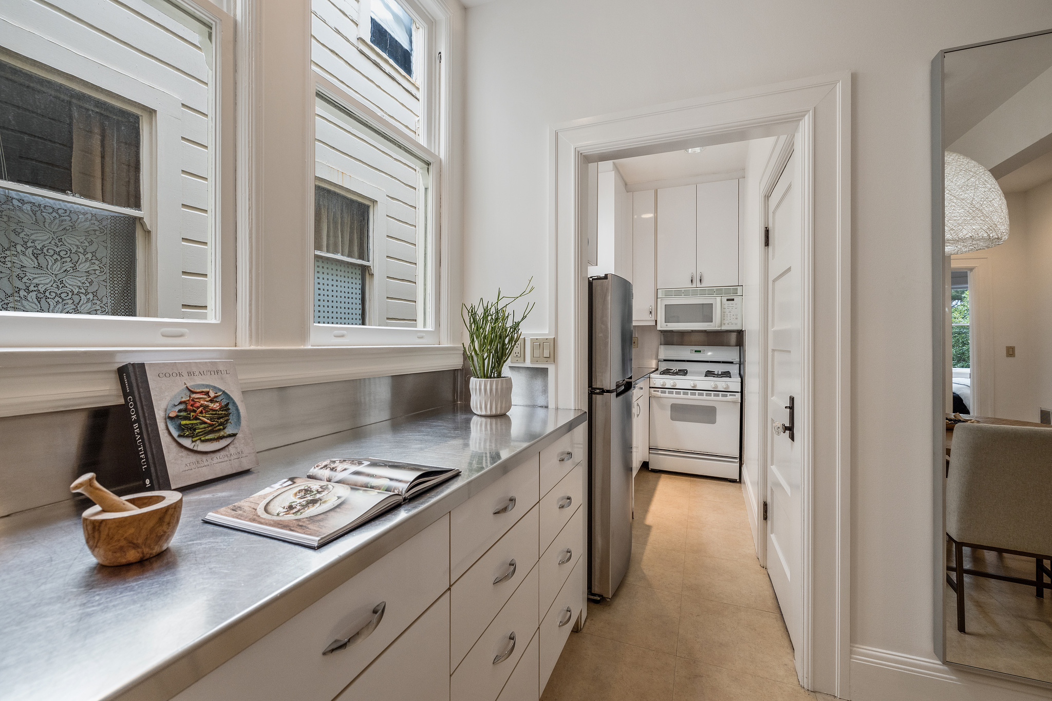 Property Photo: Kitchen, with white cabinets and galley style cooking area