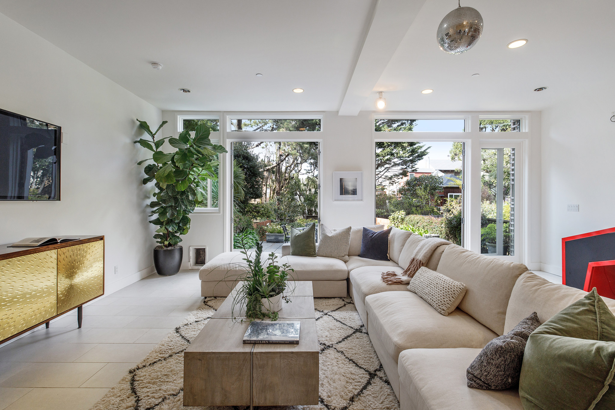 Property Photo: View of lower living area, with glass doors open showing the lush landscape beyond