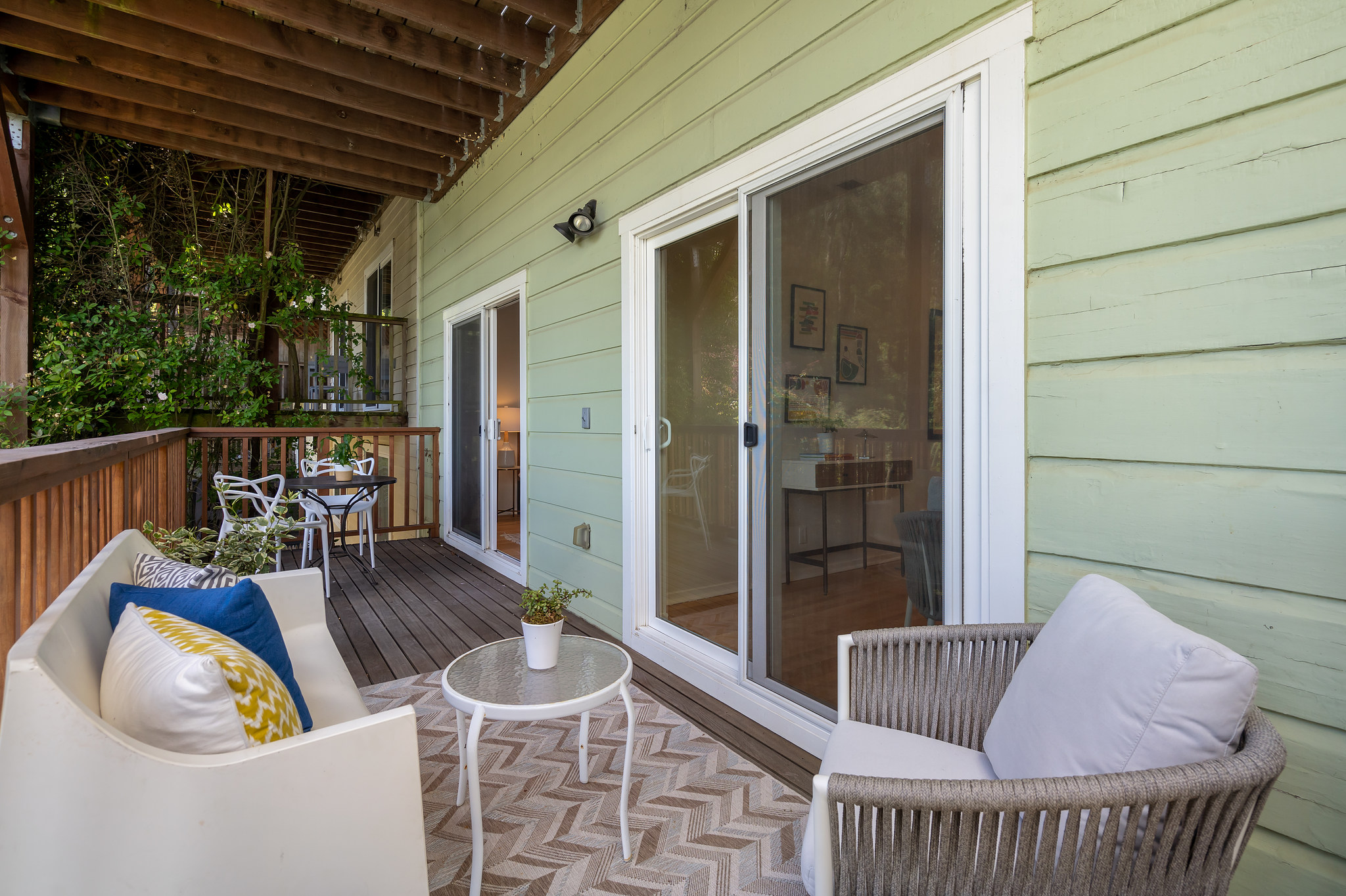 Property Photo: Lower exterior deck, showing two seating areas and two sets of sliding glass doors