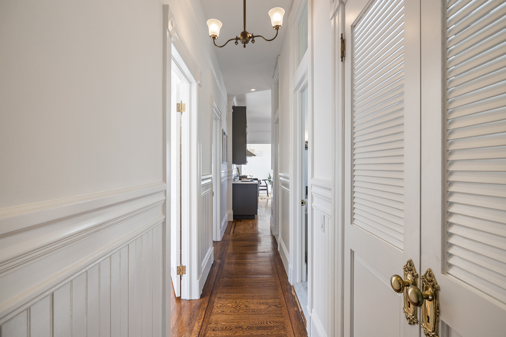 Property Photo: View of the hallway with a vintage fixture and wood floors