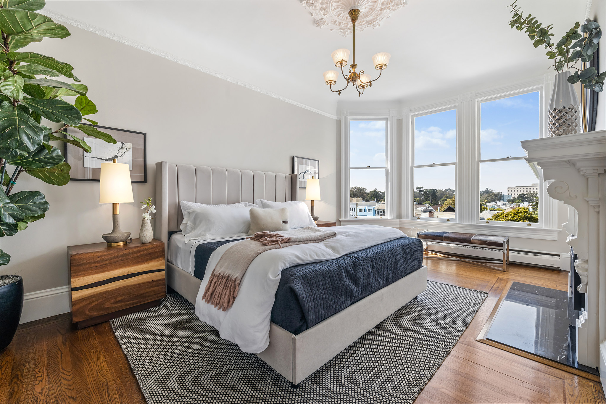 Property Photo: View of primary bedroom with large bay windows and wood floor
