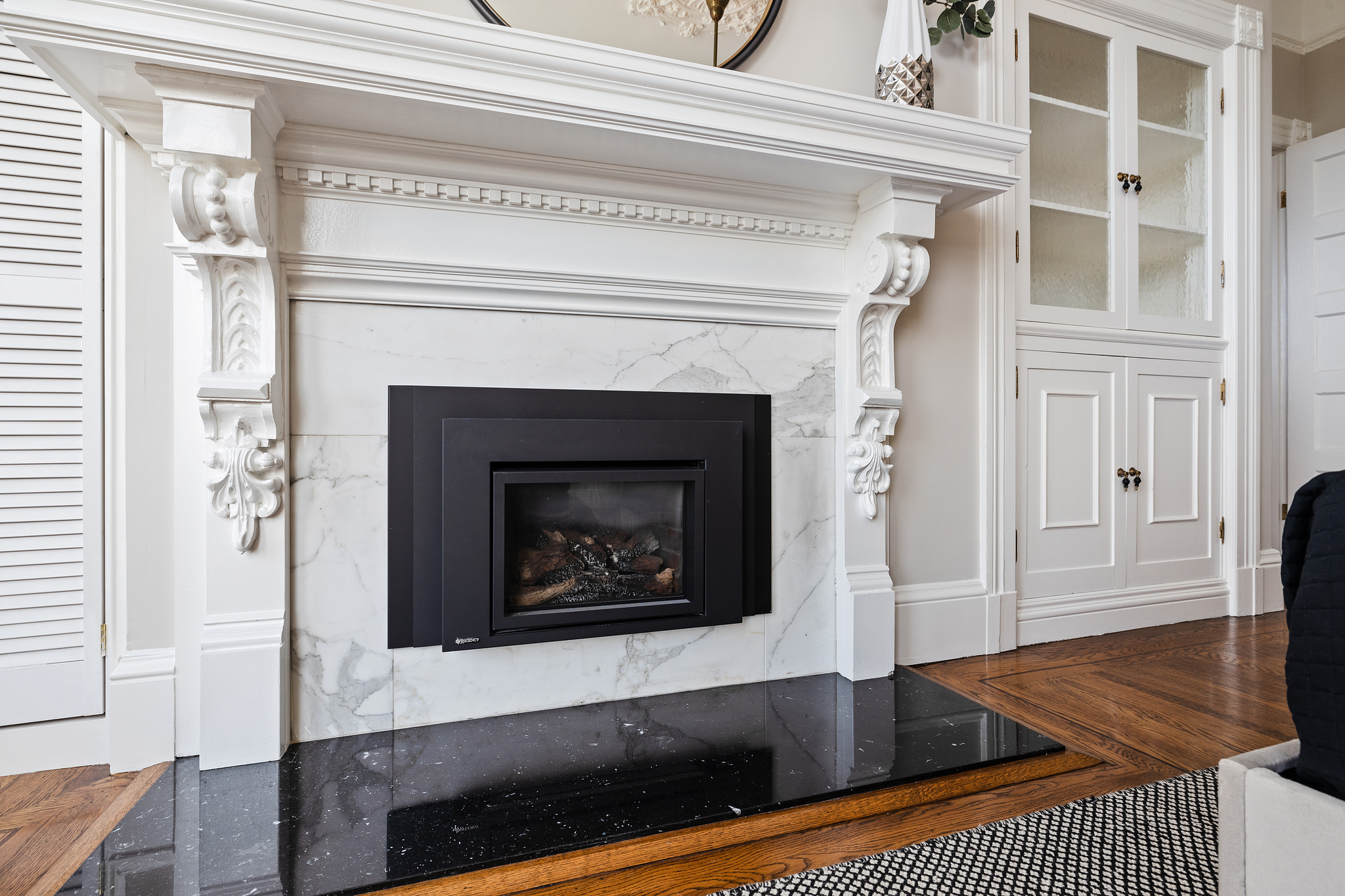 Property Photo: Close-up of the fireplace in the primary bedroom, featuring intricate woodwork