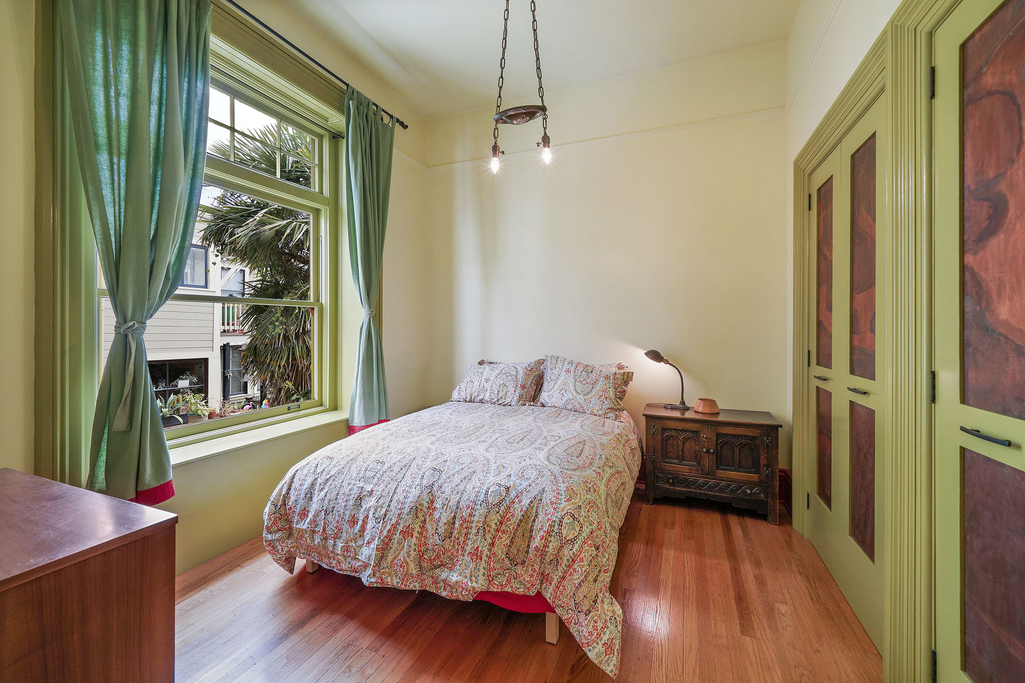 Property Photo: Bedroom with large windows, wood floors and a vintage light fixture