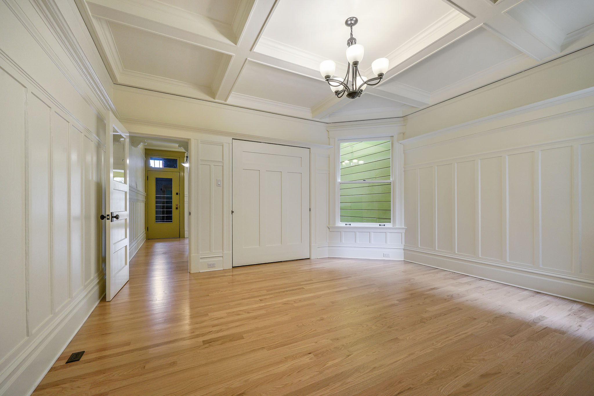 Property Photo: A large living room with white boxed wood ceilings and wainscoting 