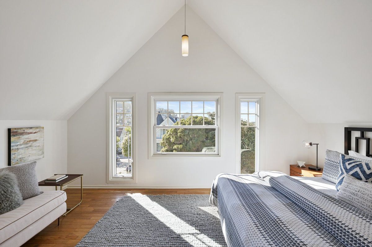 Property Photo: Primary bedroom with slanted ceilings and large windows