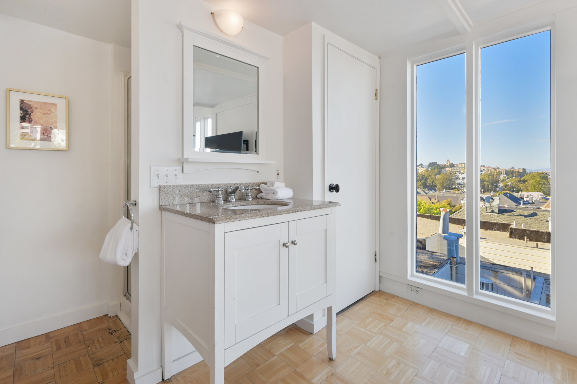 Property Photo: Close-up of the sink and vanity, with a partial view of the city in the background