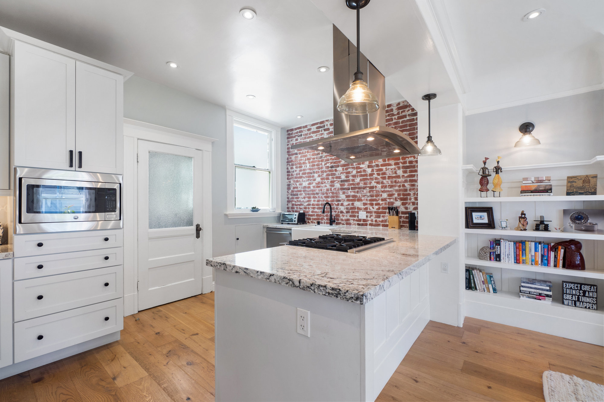 Property Photo: Kitchen with wood floors, white cabinets, and recess and pendant lighting