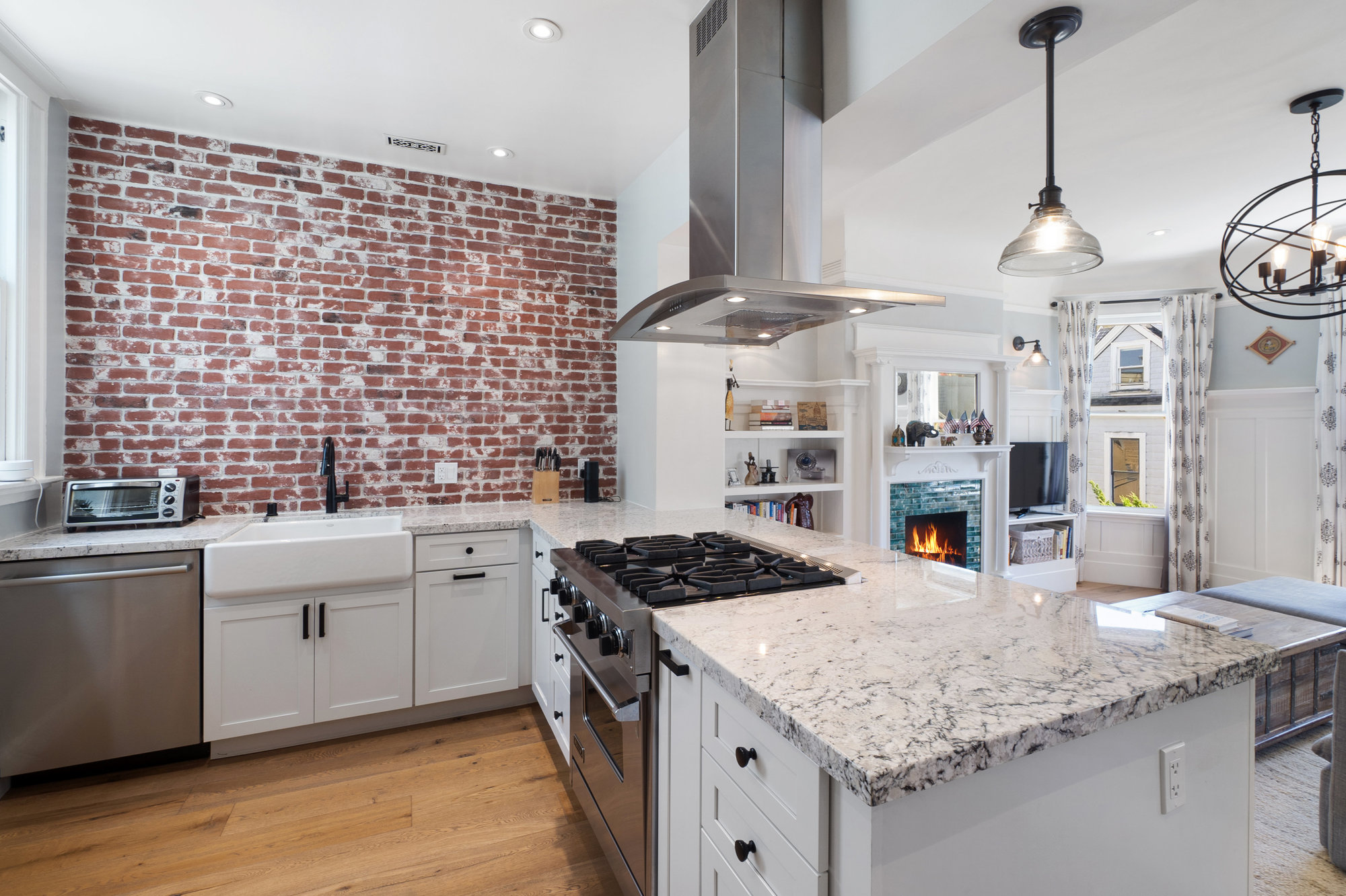 Property Photo: Kitchen with exposed brick wall and large island with stove