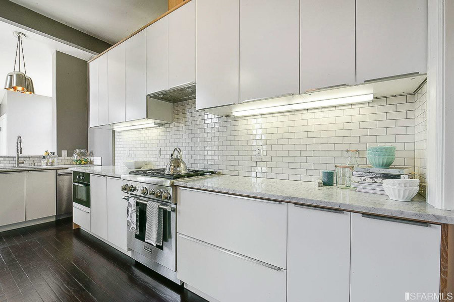 Property Photo: Kitchen, showing white cabinetry and dark flooring 