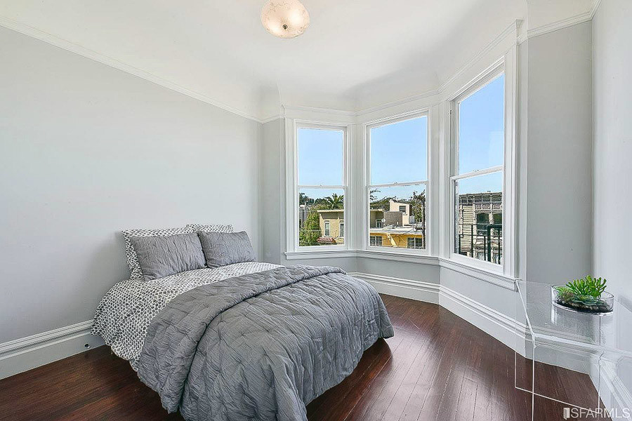 Property Photo: A bedroom, featuring wood floors and large bay windows 