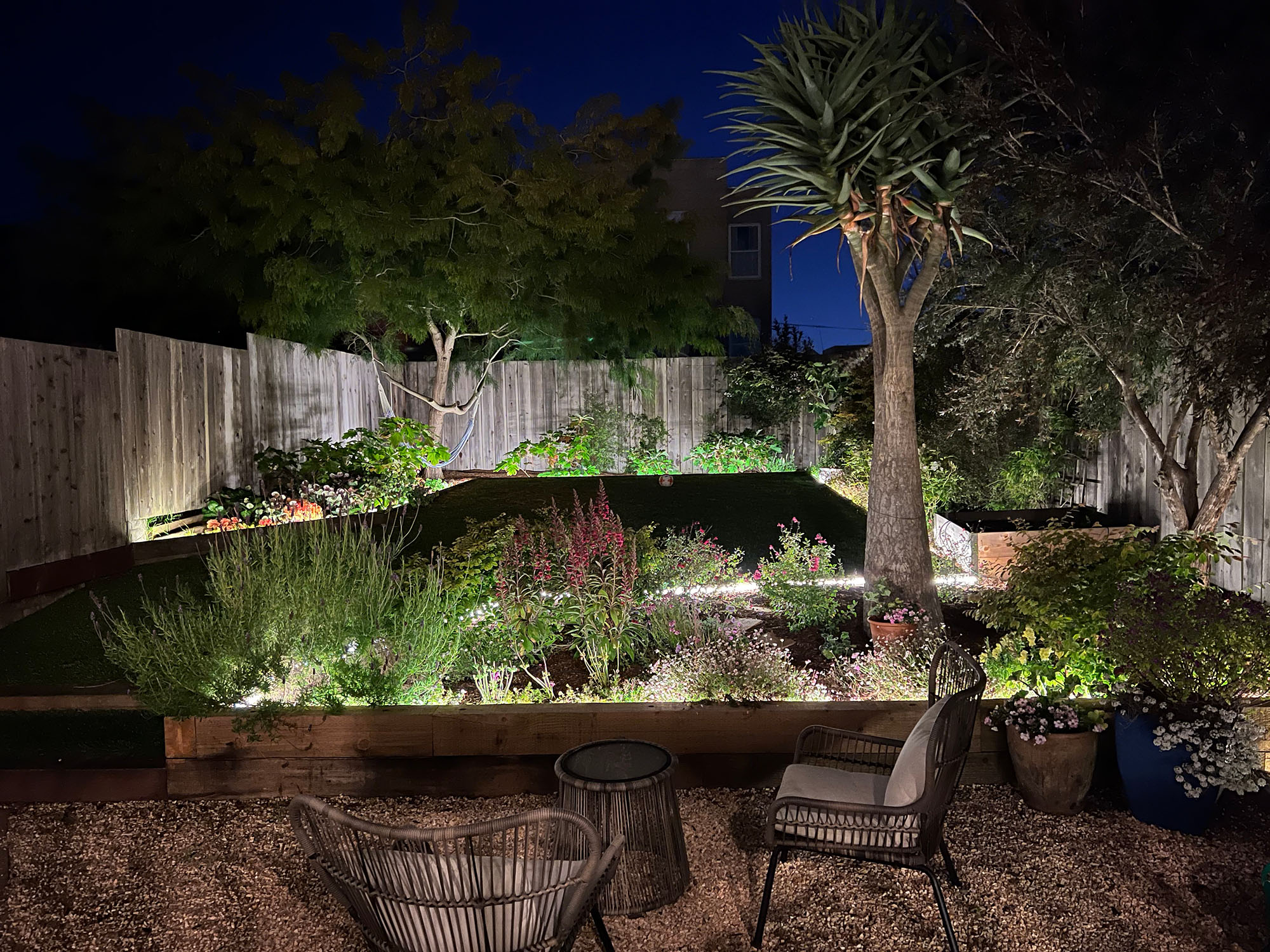 Property Photo: View of the rear yard at night, lit-up by landscape lights